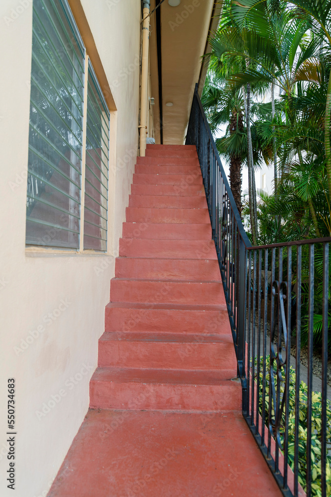 Stairs with red concrete steps and steel railings beside the building wall at Miami, Florida Stairs with red concrete steps and steel railings beside the building wall at Miami, Florida