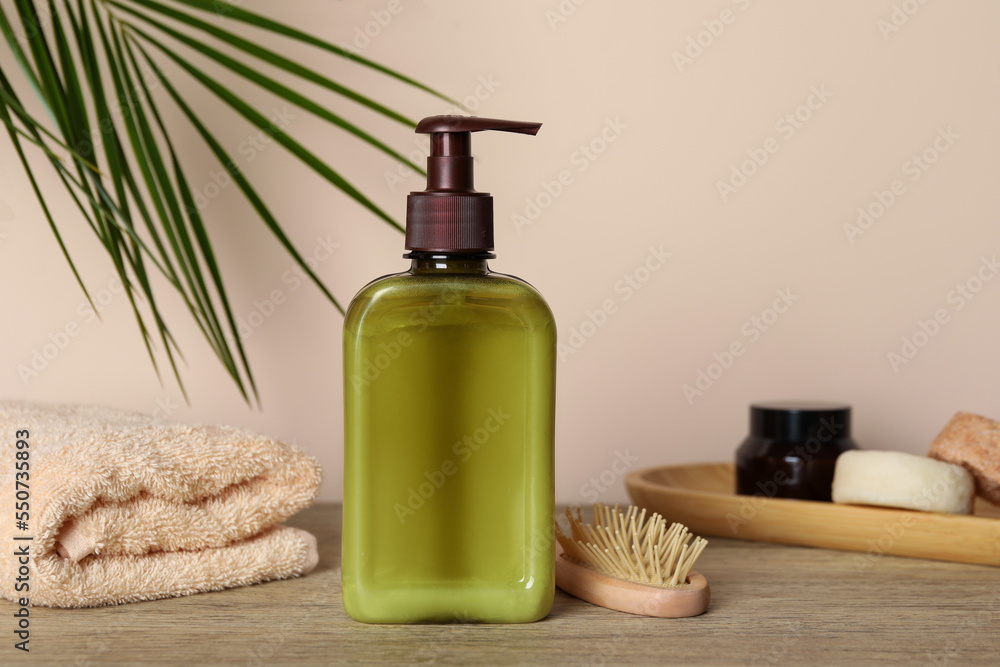 Bottle of shampoo on wooden table near beige wall - obrazy, fototapety, plakaty 