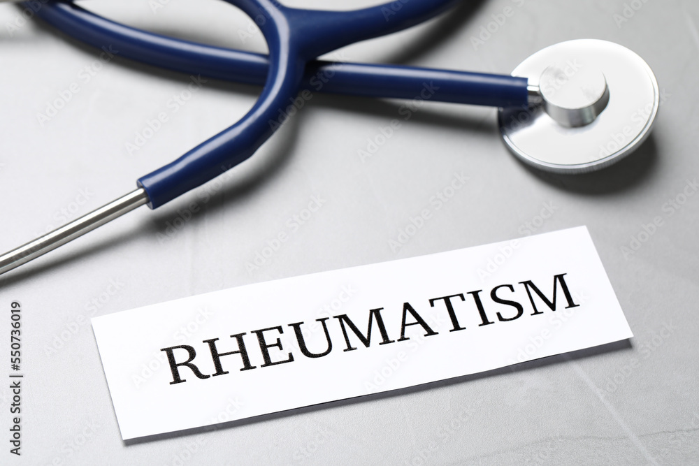 Sheet of paper with word Rheumatism and stethoscope on table, closeup Sheet of paper with word Rheumatism and stethoscope on table, closeup