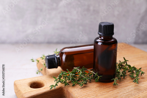 Wooden board with thyme essential oil on table  closeup