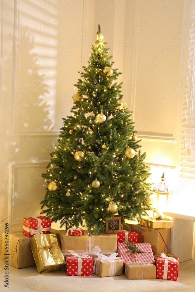 Gift boxes under Christmas tree with fairy lights indoors