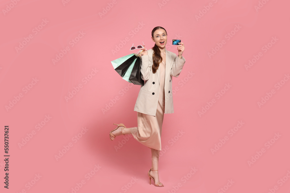 Stylish young woman with shopping bags and credit card on pink background Stylish young woman with shopping bags and credit card on pink background