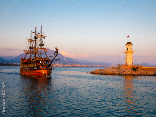 Wallpaper Mural Wooden ship and Old Alanya Deniz Feneri lighthouse in Alanya port at sunset. Popular tourist destination in Turkey. Summer travel vacation. View from embankment to beacon. Torontodigital.ca