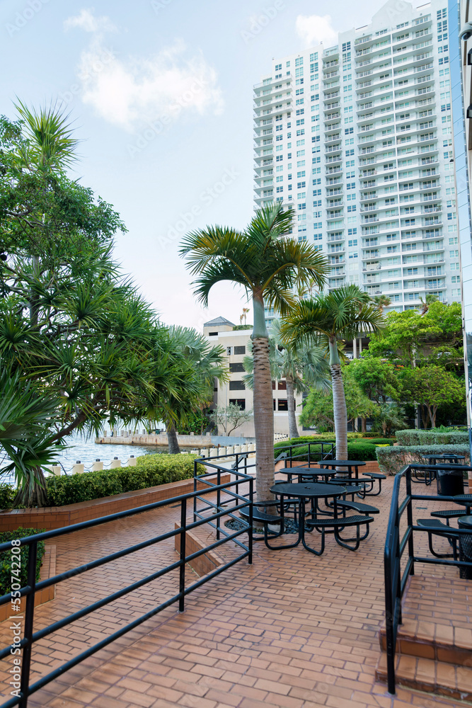 Outdoor lounge on deck near walkway with bricks metal barriers and tables with chairs at Miami, FL