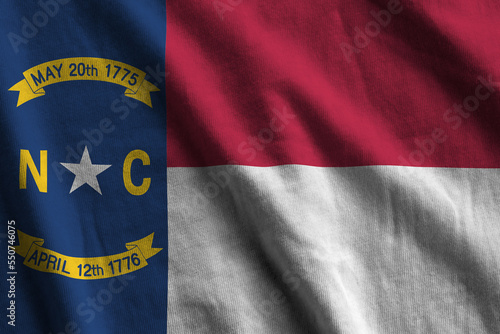 North Carolina US state flag with big folds waving close up under the studio light indoors. The official symbols and colors in fabric banner