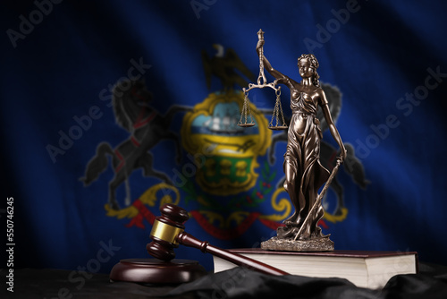 Pennsylvania US state flag with statue of lady justice, constitution and judge hammer on black drapery. Concept of judgement and punishment photo