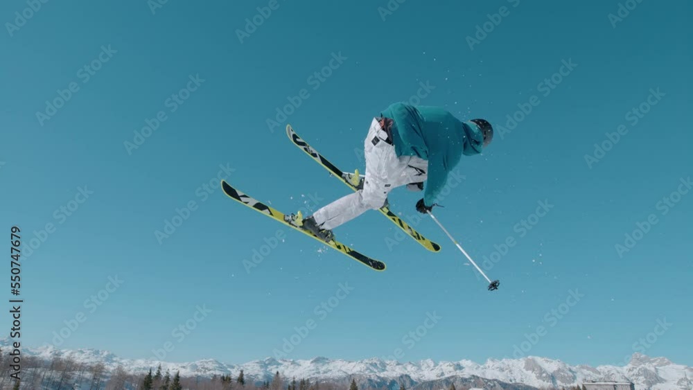 VOGEL, BOHINJ, JULIAN ALPS, SLOVENIA, MARCH 2022: SLOW MOTION: Amazing view of following freestyle skier jumping on big air kicker. Extreme athlete rotating through the air and performing grab trick. VOGEL, BOHINJ, JULIAN ALPS, SLOVENIA, MARCH 2022: SLOW MOTION: Amazing view of following freestyle skier jumping on big air kicker. Extreme athlete rotating through the air and performing grab trick.