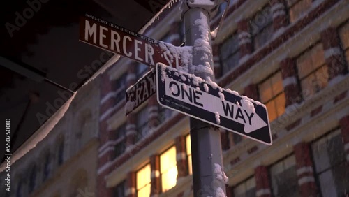 Street signs at the intersection of Mercer and Grand streets during snowy morning before sunrise