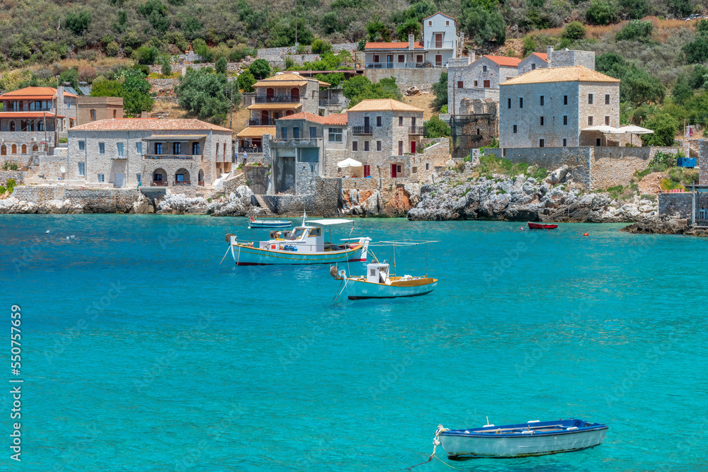 Obraz premium view of Limeni village with fishing boats in turquoise waters and the stone buildings as a background in Mani, South Peloponnese , Greece.