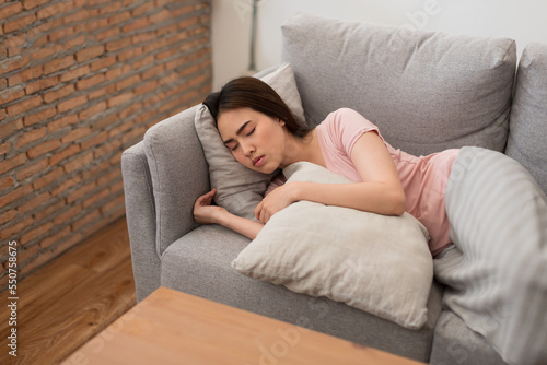 Asian young woman sleep on sofa at home. Woman is sick, unwell, cold and sleep on the sofa. Health care concept