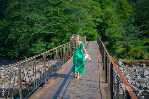 runs across the bridge in a green dress and hat in hand
