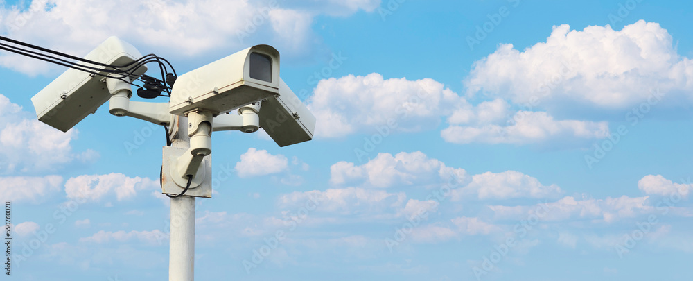 Modern CCTV surveillance security camera video equipment on pole on sky background Smart camera theft protection. safety system area control and copy space.