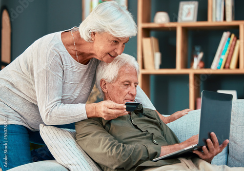 Senior couple, credit card and laptop on home sofa for ecommerce, online shopping and paying bills with fintech banking app. Old man and woman together in lounge with bank details to pay or purchase photo