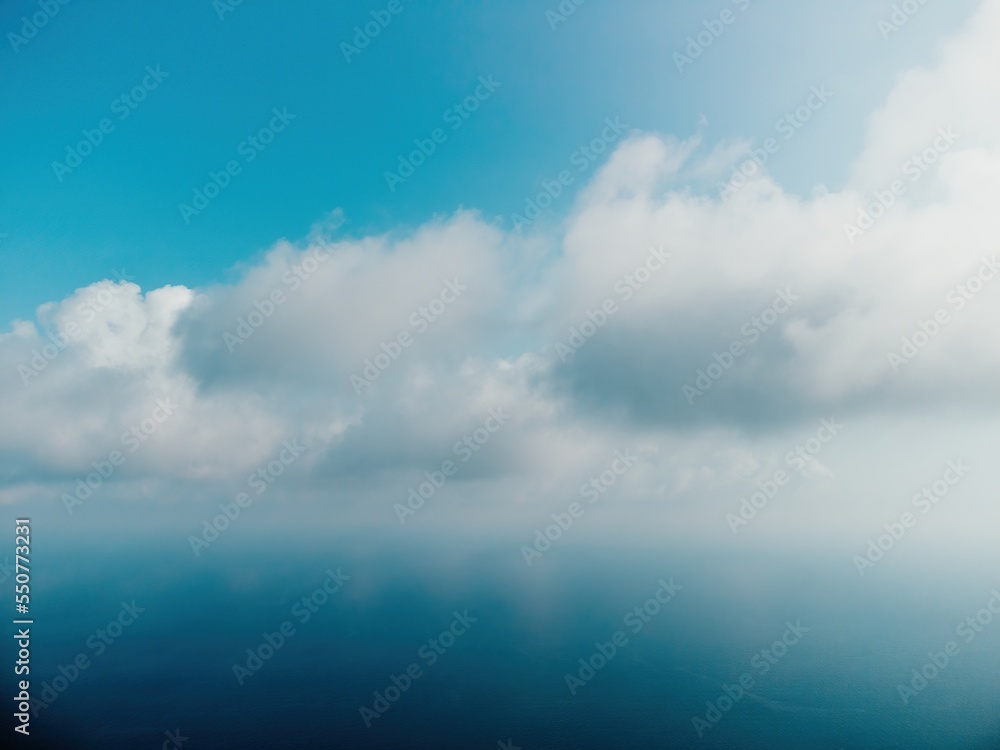 Blue sky with white clouds over calm summer panorama of the sea. Drone aerial view. Abstract aerial nature summer ocean sunset sea and sky background. Horizon. No people. Holiday and vacation concept Blue sky with white clouds over calm summer panorama of the sea. Drone aerial view. Abstract aerial nature summer ocean sunset sea and sky background. Horizon. No people. Holiday and vacation concept