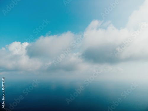 Blue sky with white clouds over calm summer panorama of the sea. Drone aerial view. Abstract aerial nature summer ocean sunset sea and sky background. Horizon. No people. Holiday and vacation concept © panophotograph