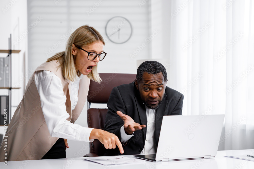 Fotka „Angry female boss scolding African American office worker. demanding manager-leader is annoyed by laziness and mistakes in the work of an employee. Authoritarian leadership, malfeasance, racism“ ze služby Stock