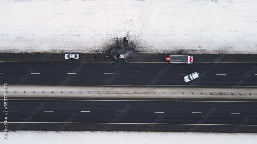 Disaster - burned out car on the edge of the motorway in winter, aerial view. Near the fire and police cars. Help and rescue concept, 911 service. White snow on the side of the road. UHD 4K Disaster - burned out car on the edge of the motorway in winter, aerial view. Near the fire and police cars. Help and rescue concept, 911 service. White snow on the side of the road. UHD 4K