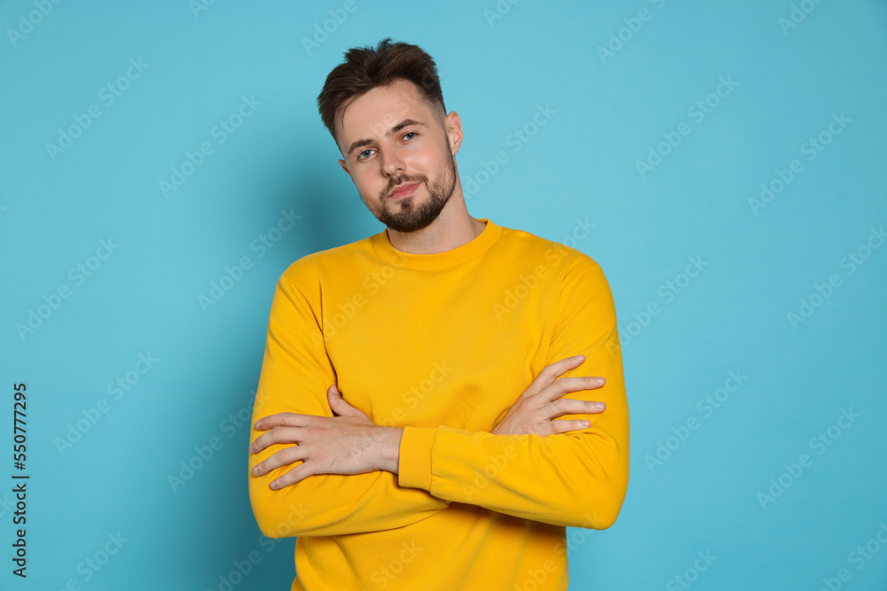 Handsome man in yellow sweatshirt on light blue background Handsome man in yellow sweatshirt on light blue background