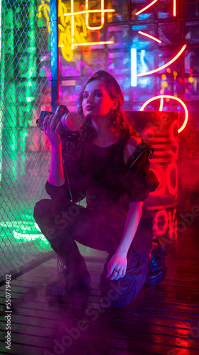 Caucasian woman with a gas mask in her hands in a neon studio. 