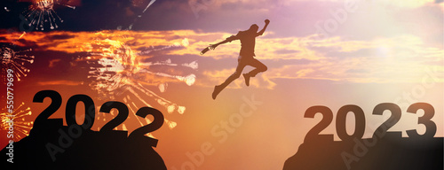 New year concept of 2023. New year's card. Silhouette of a man jumping over a cliff with covid and mask jumping to 2023, Happy new year concept.motivation, challenge, Business.Medical Healthcare.