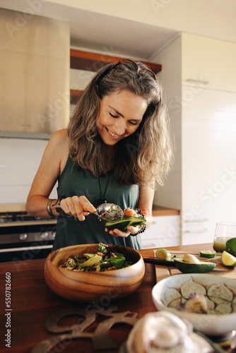 Happy vegetarian woman preparing a delicious buddha bowl at home