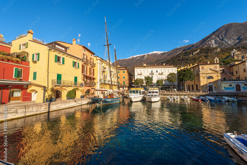 Malcesine village. Port with small boats and ferries moored and colorful houses. Famous tourist resort on the coast of Lake Garda (Lago di Garda). Verona province, Veneto, Italy, southern Europe.