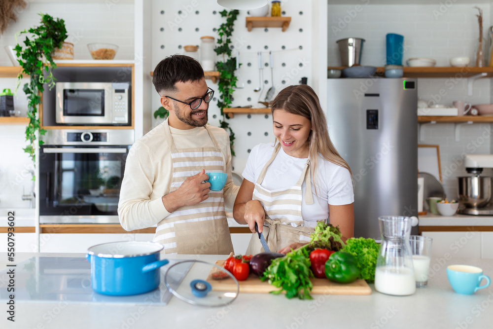 Portrait of happy young couple cooking together in the kitchen at home. romantic Attractive young woman and handsome man are enjoying spending time together while standing on light modern kitchen.
