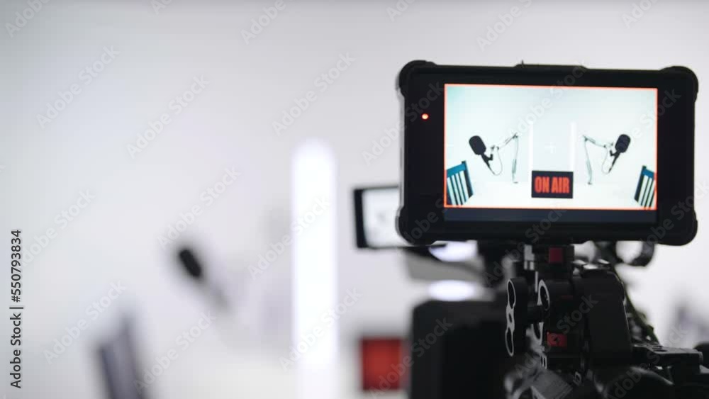 Camera recording white podcast studio with led tubes zoom out of monitor 4K