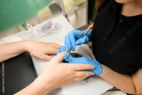 Close-up of the hands of the master in gloves making correction of nails and cuticles