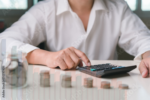 Businessman using calculator to calculate  Stacking coins  graph icon  a jar of coins. Plan revenue and expenses  target success growth  finance profit management planning 2023 concept.