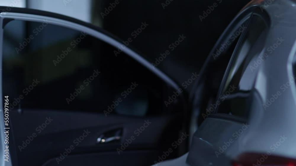 Woman opens car door and enters vehicle at night Woman opens car door and enters vehicle at night