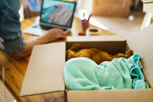 Box parcel with clothes inside on desk, reselling pre owned clothes online concept.