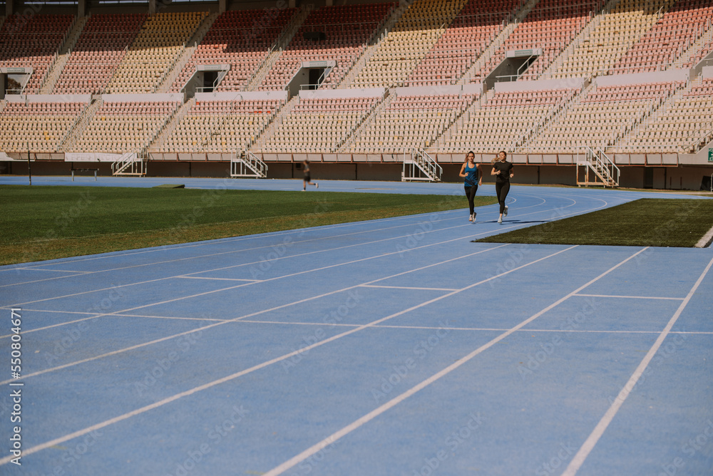 Obraz premium Gorgeous girls jogging together at the stadium