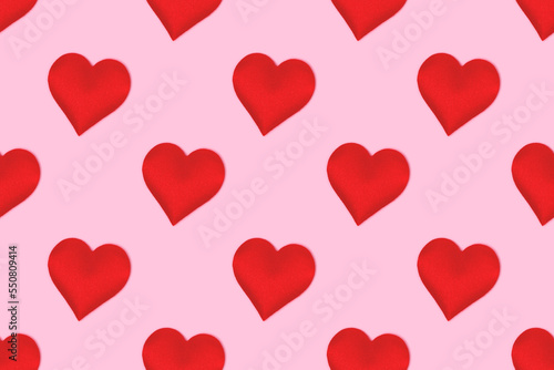 Repetitive pattern made of red hearts. Minimal concept on a pink background.
