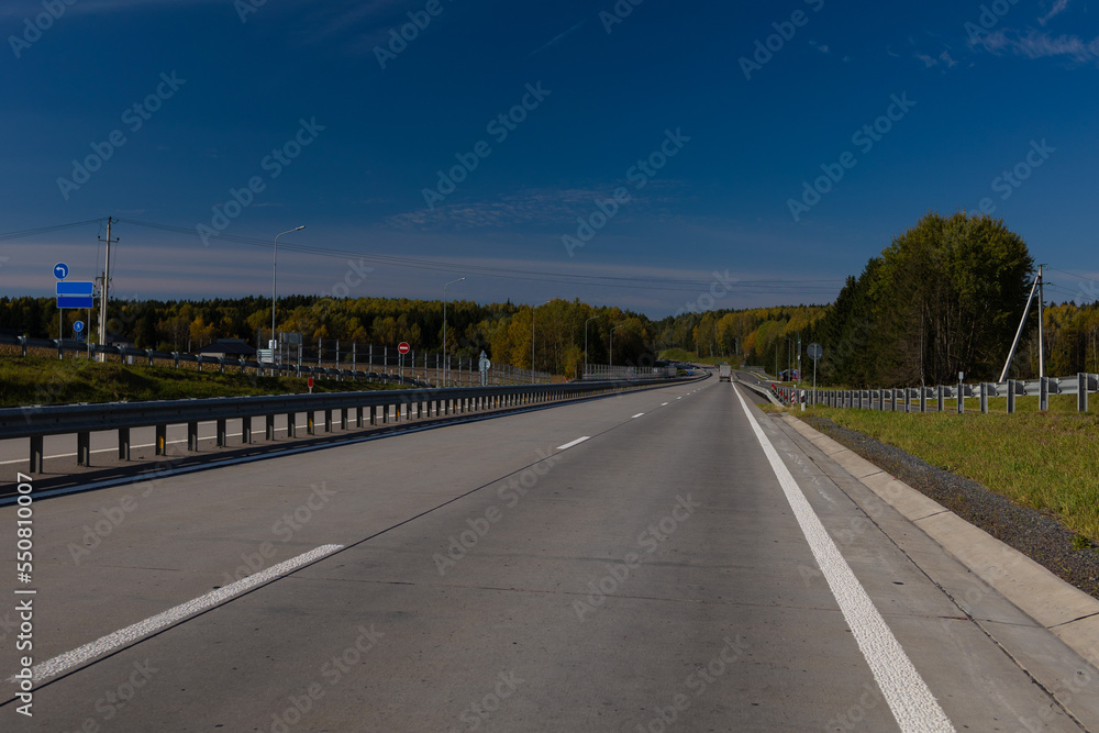 Fototapeta premium Highway wide road, transport and blue sky with clouds on a summer day