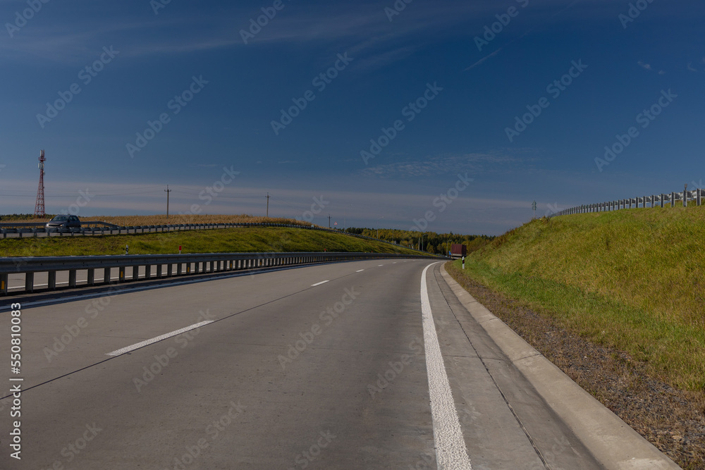 Fototapeta premium Highway wide road, transport and blue sky with clouds on a summer day