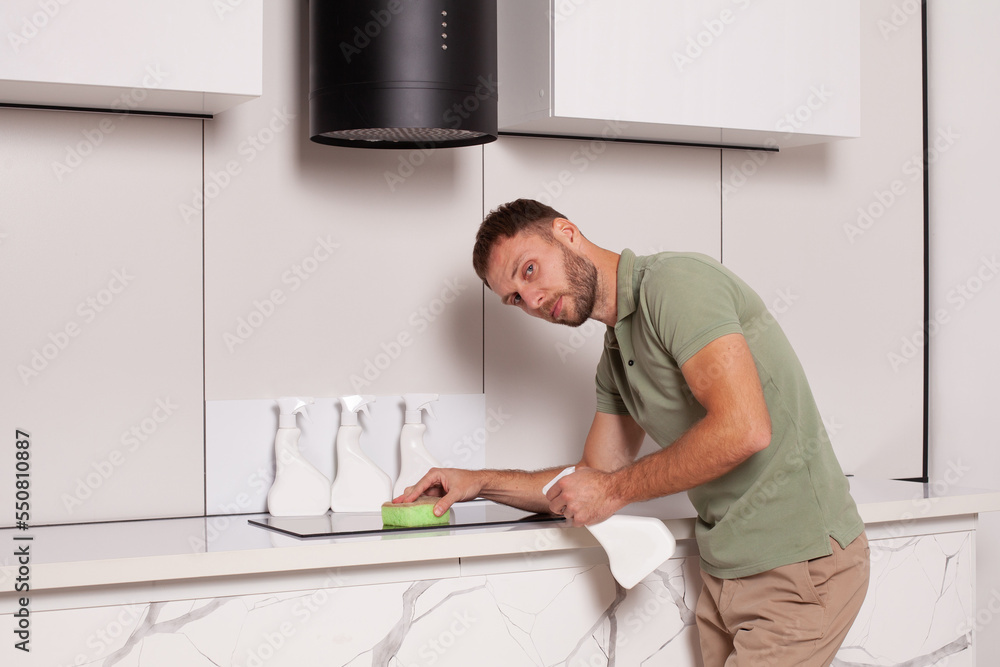 Man cleaning the cooker in the kitchen holding bottle with blank label