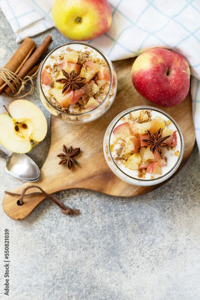 Homemade dessert with yogurt, granola, caramel apples and cinnamon on a stone table. Healthy breakfast granola, healthy lifestyle. View from above. Copy space.