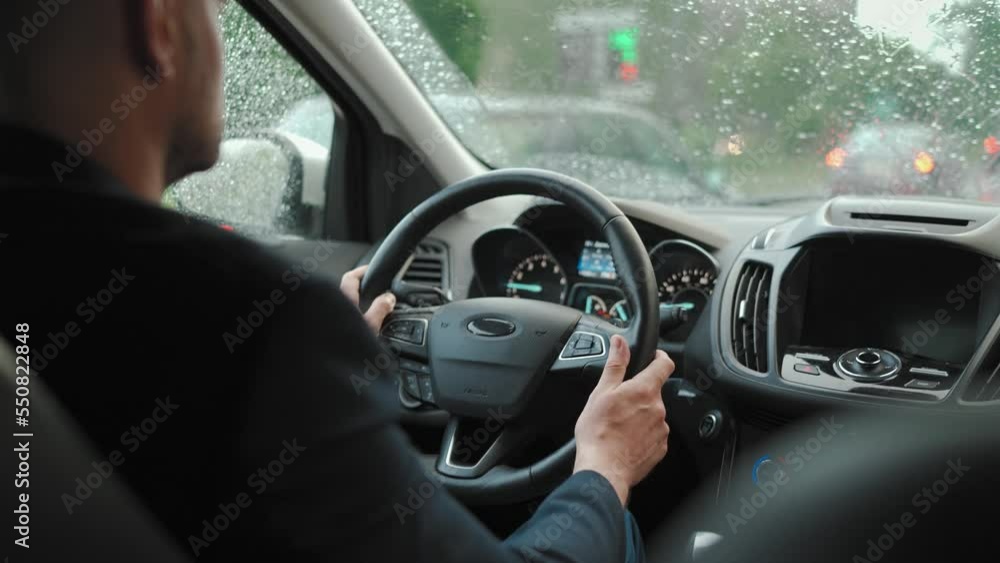 Man drives a car along the road in the city during the rain. Man drives a car along the road in the city during the rain.