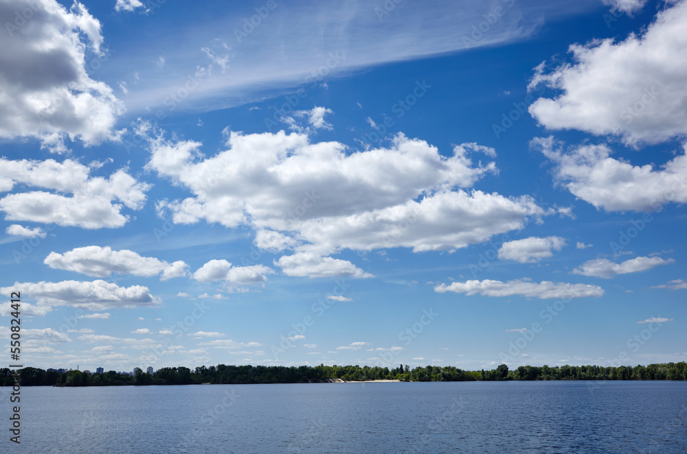 Beautiful river landscape. Lake surface on a sunny perfect day. The surface of the water against the background of trees and a blue sky. Blurred image, selective focus Beautiful river landscape. Lake surface on a sunny perfect day. The surface of the water against the background of trees and a blue sky. Blurred image, selective focus