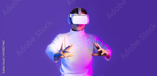 Metaverse asian man in white long sleeve t-shirt wear vr headset watching touching on purple color background.