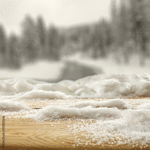 Wooden desk cover of snow flakes and winter landscape of free space. 