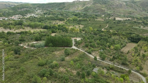 Vuelo de dron hacia atrás con pequeño soto y pueblo de fondo en Galicia photo