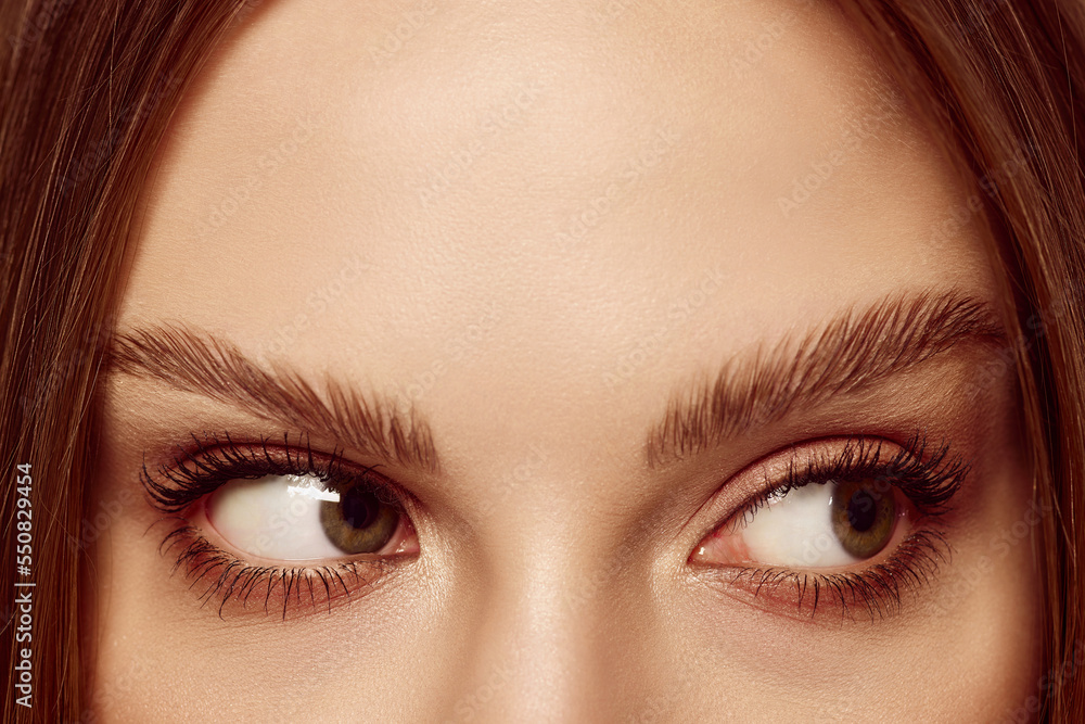 Fototapeta premium Sideways glance. Close up of beautiful brown female eyes. Perfect trendy eyebrow. Concept of vision, contact lenses, trendy eyebrow makeup concept.