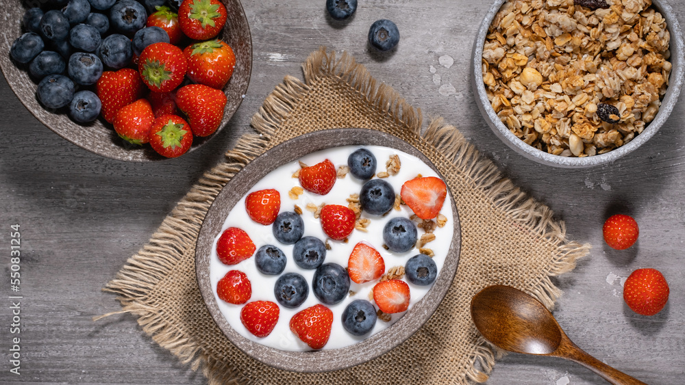Bowl of homemade granola with yogurt and fresh berries on wooden background from top view Bowl of homemade granola with yogurt and fresh berries on wooden background from top view