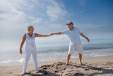coppia di anziani balla felice in spiaggia sulla riva del mare