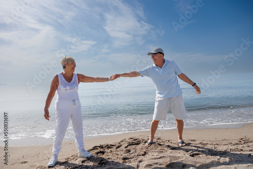 coppia di anziani balla felice in spiaggia sulla riva del mare photo