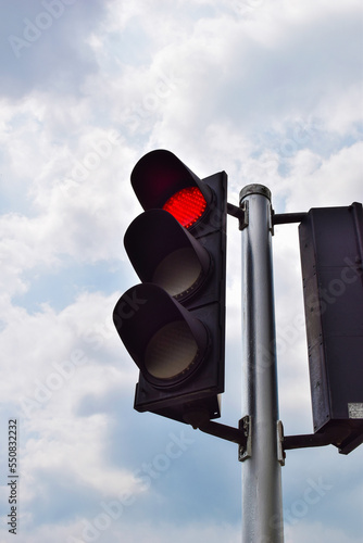 Red traffic light on sky background.