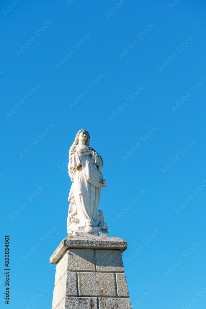 single caring woman statue against a bright blue sky