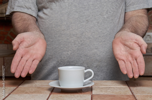 Male hands have just placed a coffee cup on a tiled kitchen table